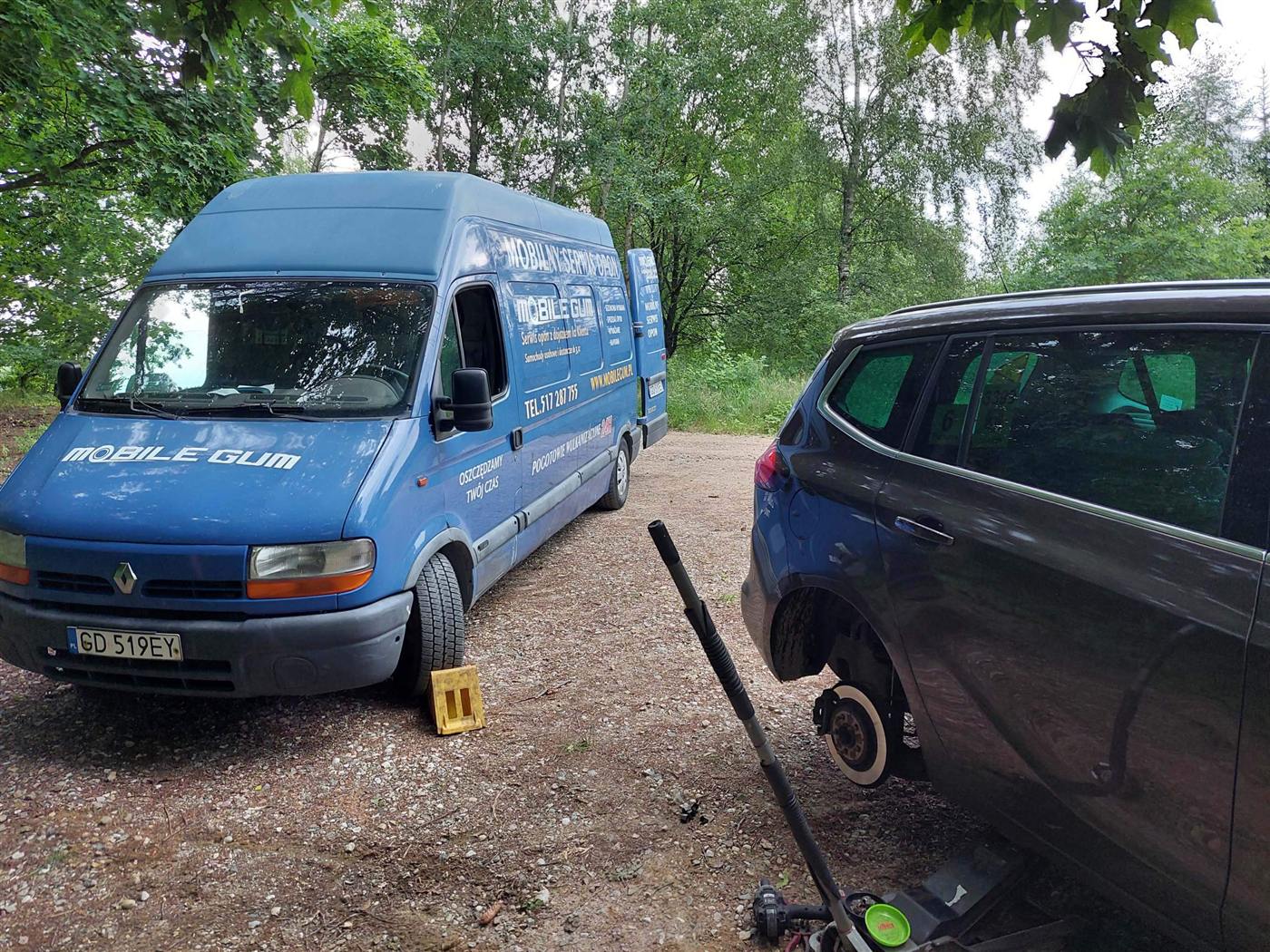 Niebieski bus Mobile Gum, mobilny serwis opon, podczas wymiany koła w samochodzie klienta